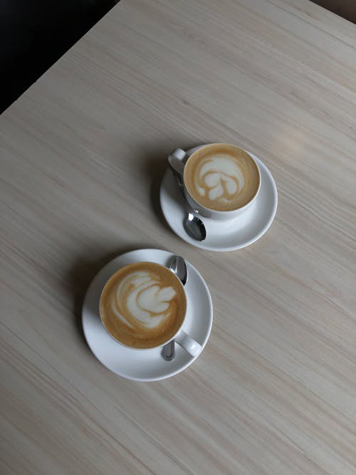 ahşap masa üstü, bardak kahve, cappuccino içeren Ücretsiz stok fotoğraf
