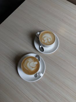 Two cappuccino cups with latte art on a wooden table. Perfect for coffee lovers.