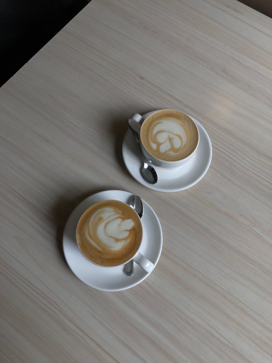 Two cappuccino cups with latte art on a wooden table. Perfect for coffee lovers.