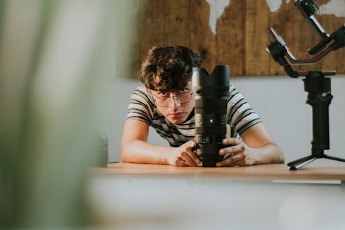 Man in Striped Shirt Holding a Camera Lens