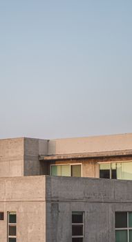 Exterior view of a modern concrete building with glass windows during sunset.
