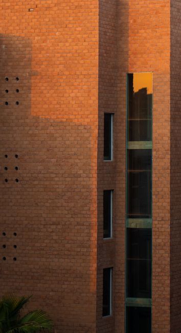 Fotomural Toma vertical de un edificio moderno de ladrillo con ventanas de vidrio reflectantes al atardecer.