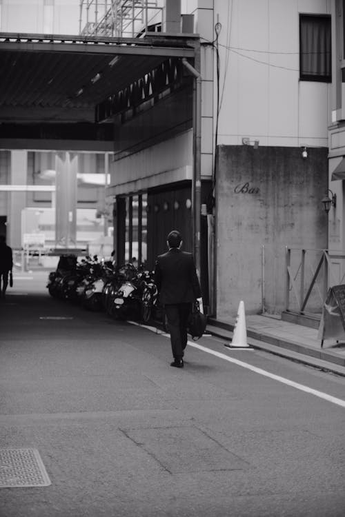 Grayscale Photo of Man Walking on a Street