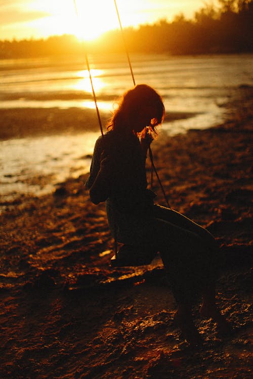 Silhouette of Woman Sitting on a Wooden Swing