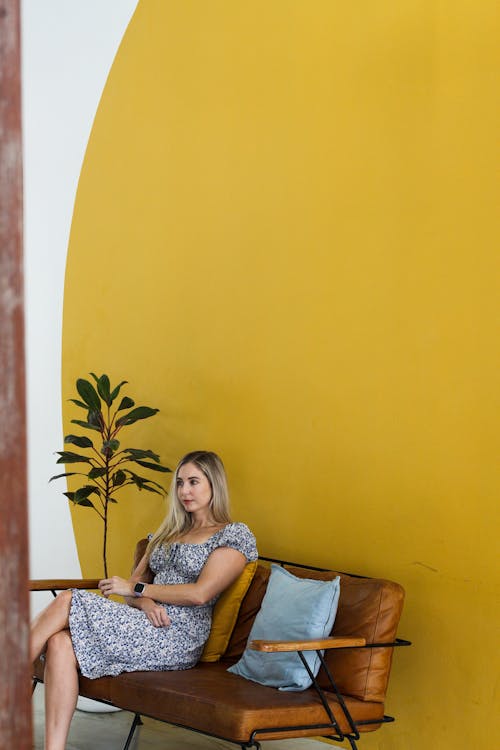 Woman Sitting on a Leather Couch Placed on a Yellow Wall