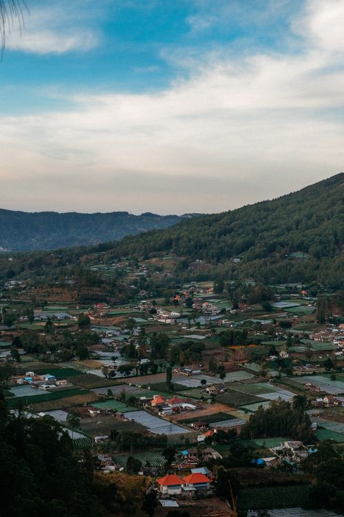 Free Aerial view of Bali's verdant landscape with villages and mountains under a cloudy sky. Stock Photo