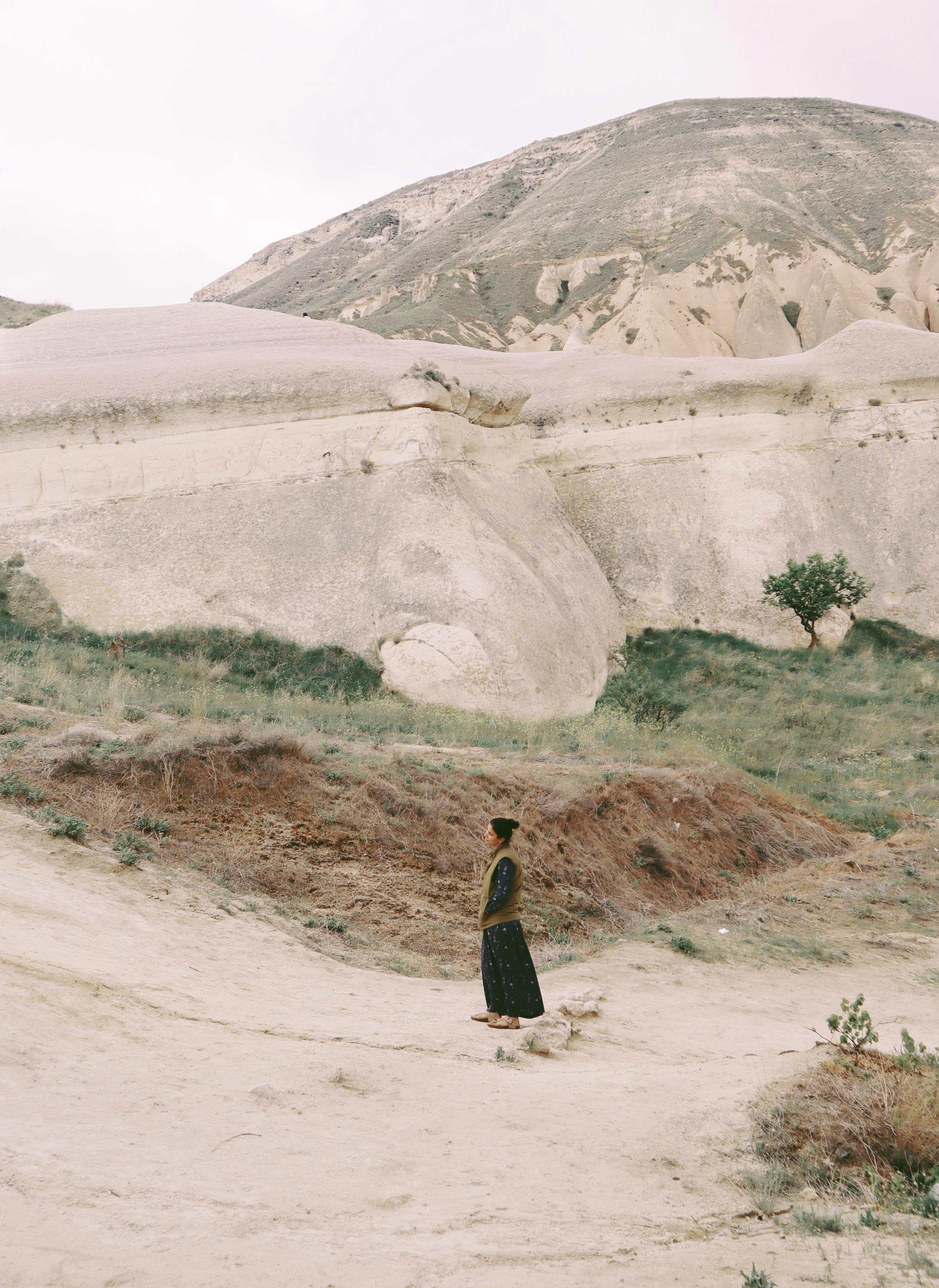A woman stands alone in a serene mountainous landscape in Turkey.