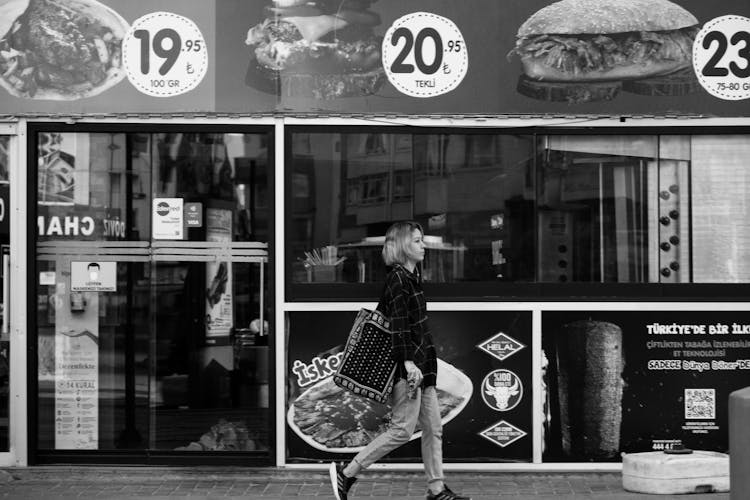 Woman In Plaid Dress Shirt Walking In Front Of A Restaurant