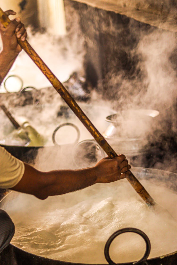 Person Stirring Pot With Wooden Stick 