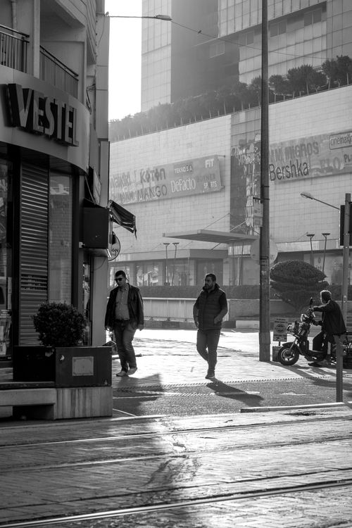 Free Monochrome photo of a city street with pedestrians walking near buildings. Stock Photo