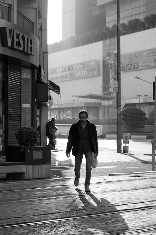 Black and White Photo of a Man Walking on the Street