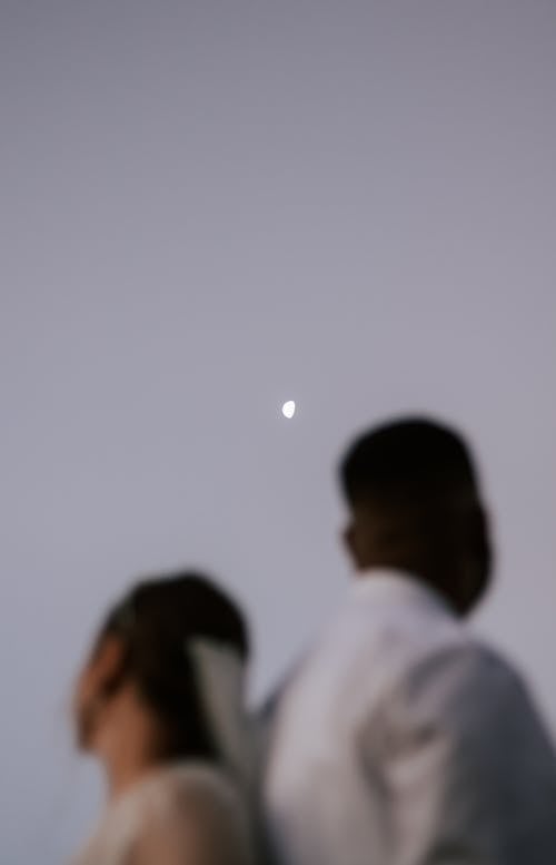A Couple Under a Half Moon on a Gray Sky