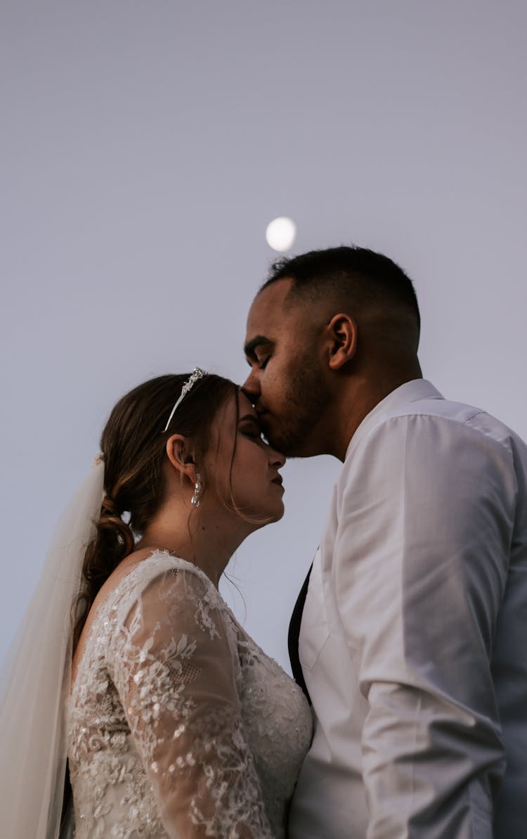 A Man Kissing A Bride On Her Forehead 