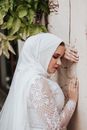 Woman in White Hijab Leaning on White Wall