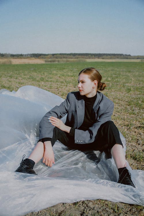 Woman Sitting on Plastic in a Field