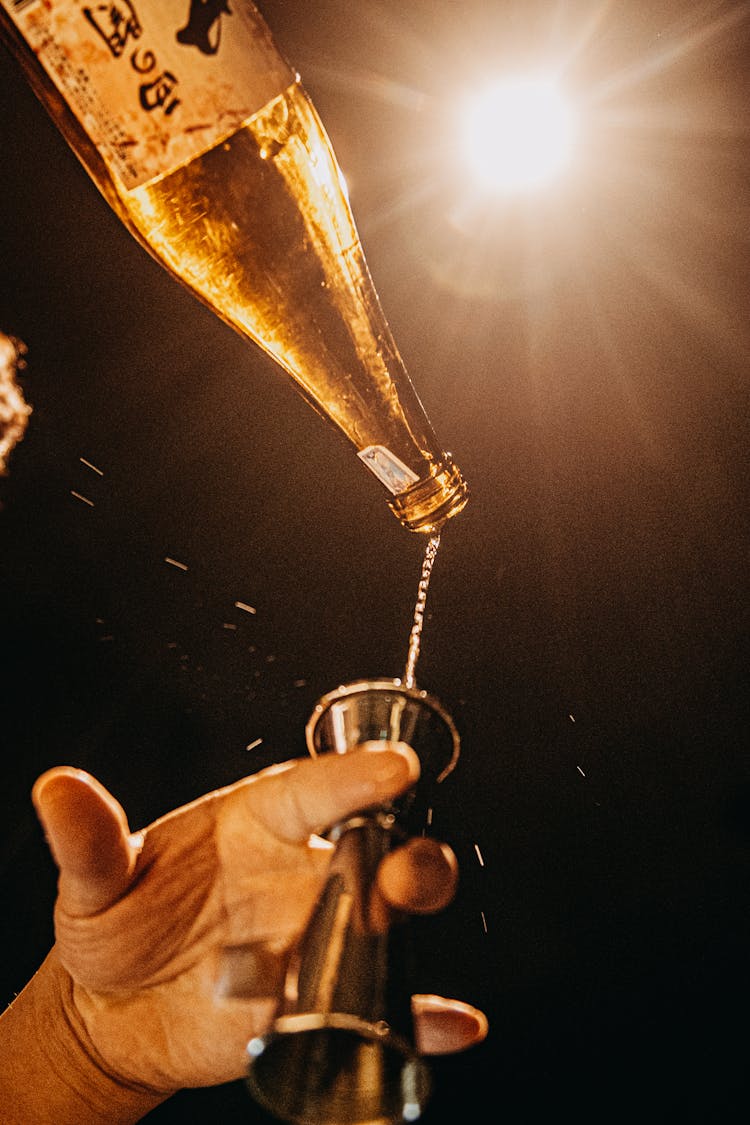 Person Pouring Wine Into A Jigger