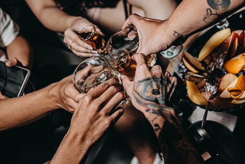 Free A close-up of friends clinking glasses in a festive setting, highlighting tattoos and diverse hands. Stock Photo
