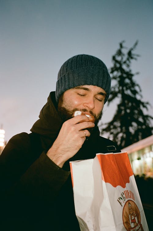 Man Wearing a Beanie Eating Donut