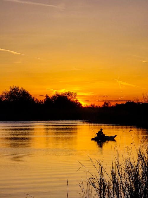 Silhouette of a Person on a Boat in the Lake