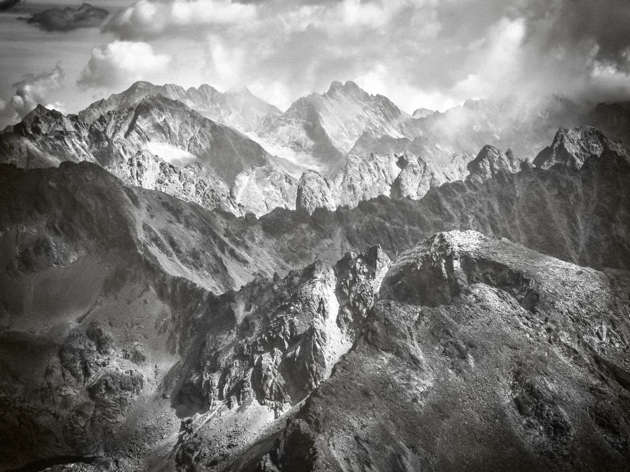 spectacular black and white view of rugged mountain ranges under a clo