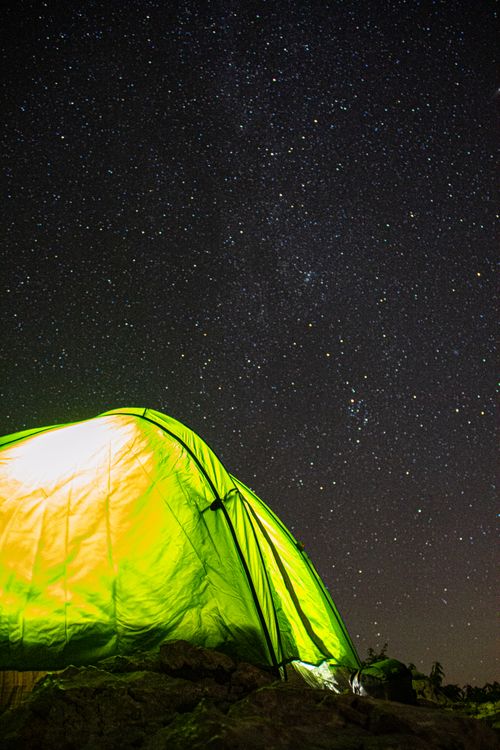 Free A glowing tent under a vast starry sky in Lombardy, Italy, perfect for an adventurous night. Stock Photo