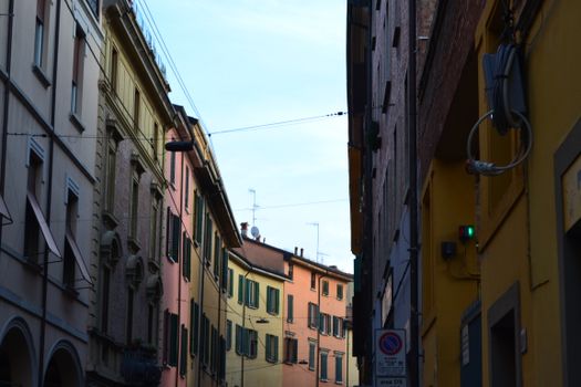 Charming view of vibrant buildings lining a narrow street in Bologna, Italy.
