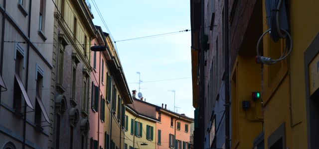 Charming view of vibrant buildings lining a narrow street in Bologna, Italy.