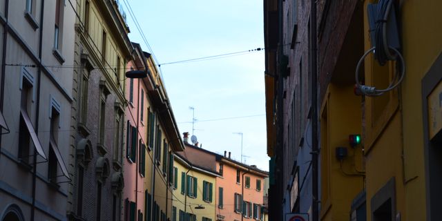 Charming view of vibrant buildings lining a narrow street in Bologna, Italy.