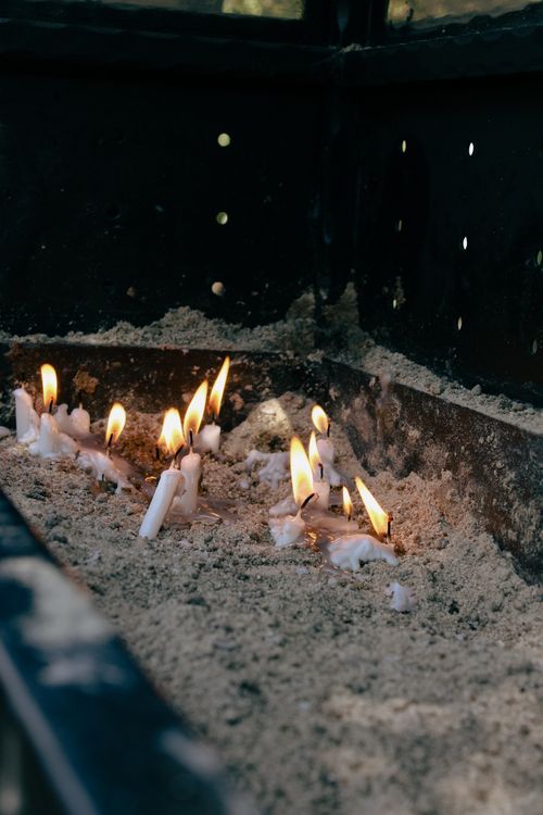 Free Close-up of lit candles in sand with dark background. Stock Photo