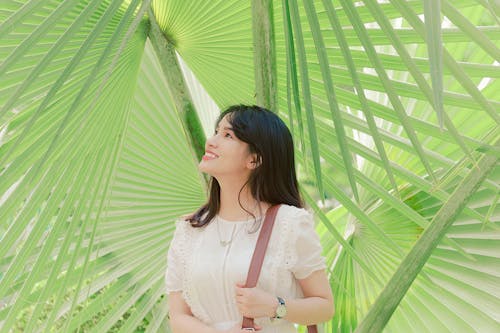Smiling Woman Standing Near Green Leaf Plants
