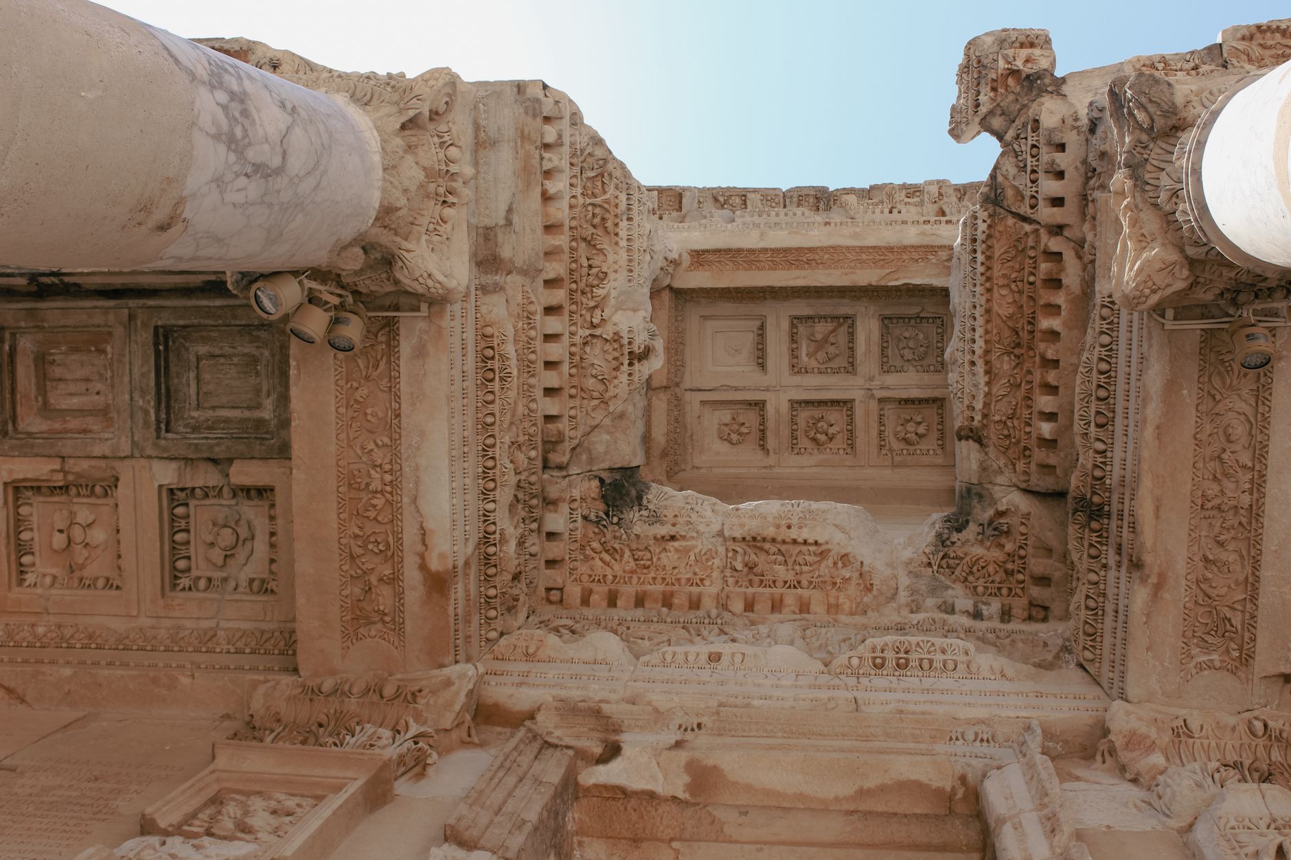 Detailed view of ancient decorative stone ruins against a clear sky.
