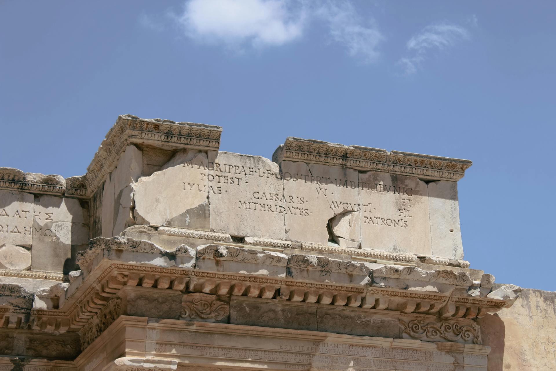 Detailed view of ancient Roman ruins showcasing inscriptions and architectural details under a clear sky.