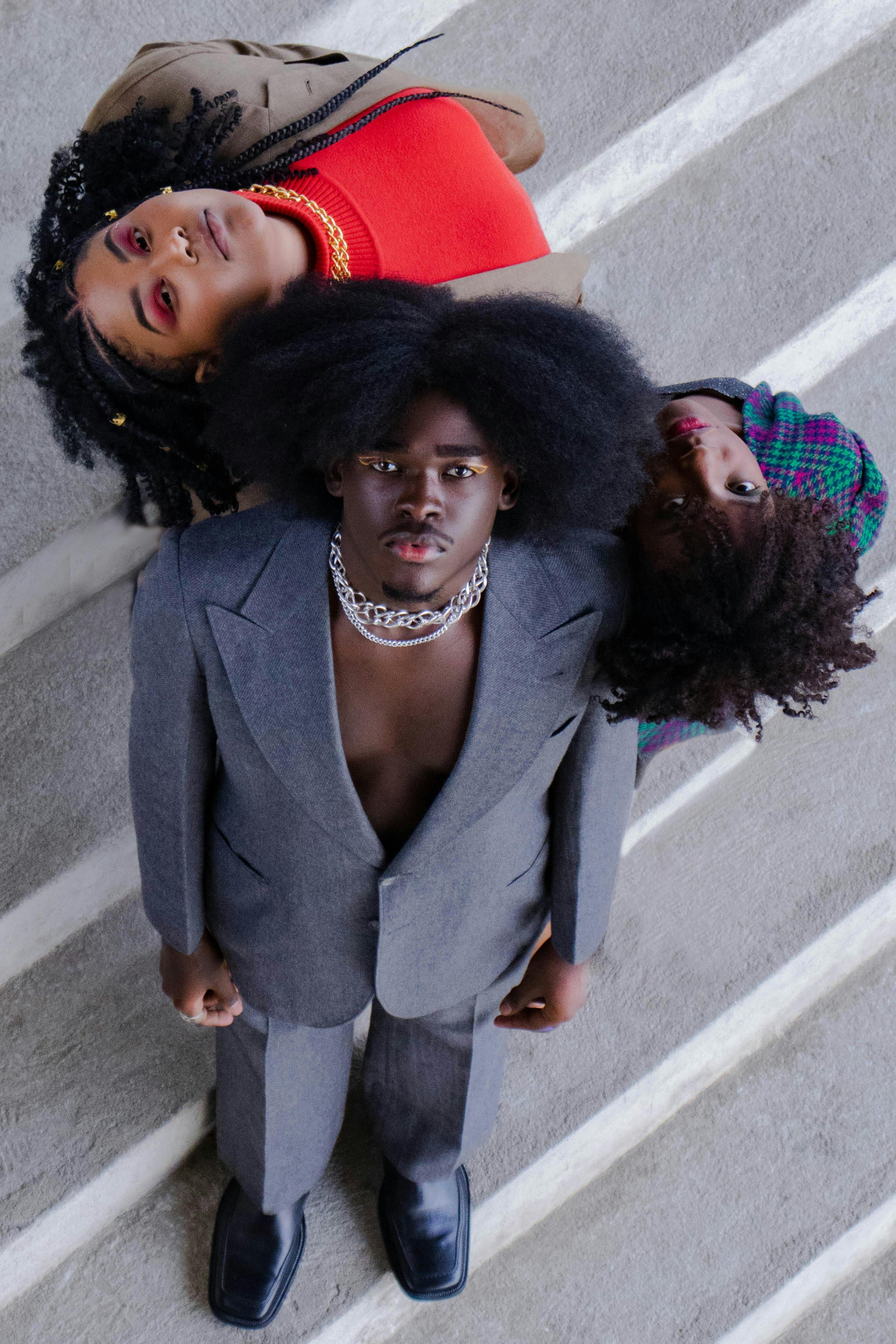 Three fashionable individuals pose creatively for an urban portrait, showcasing bold style and attitude.