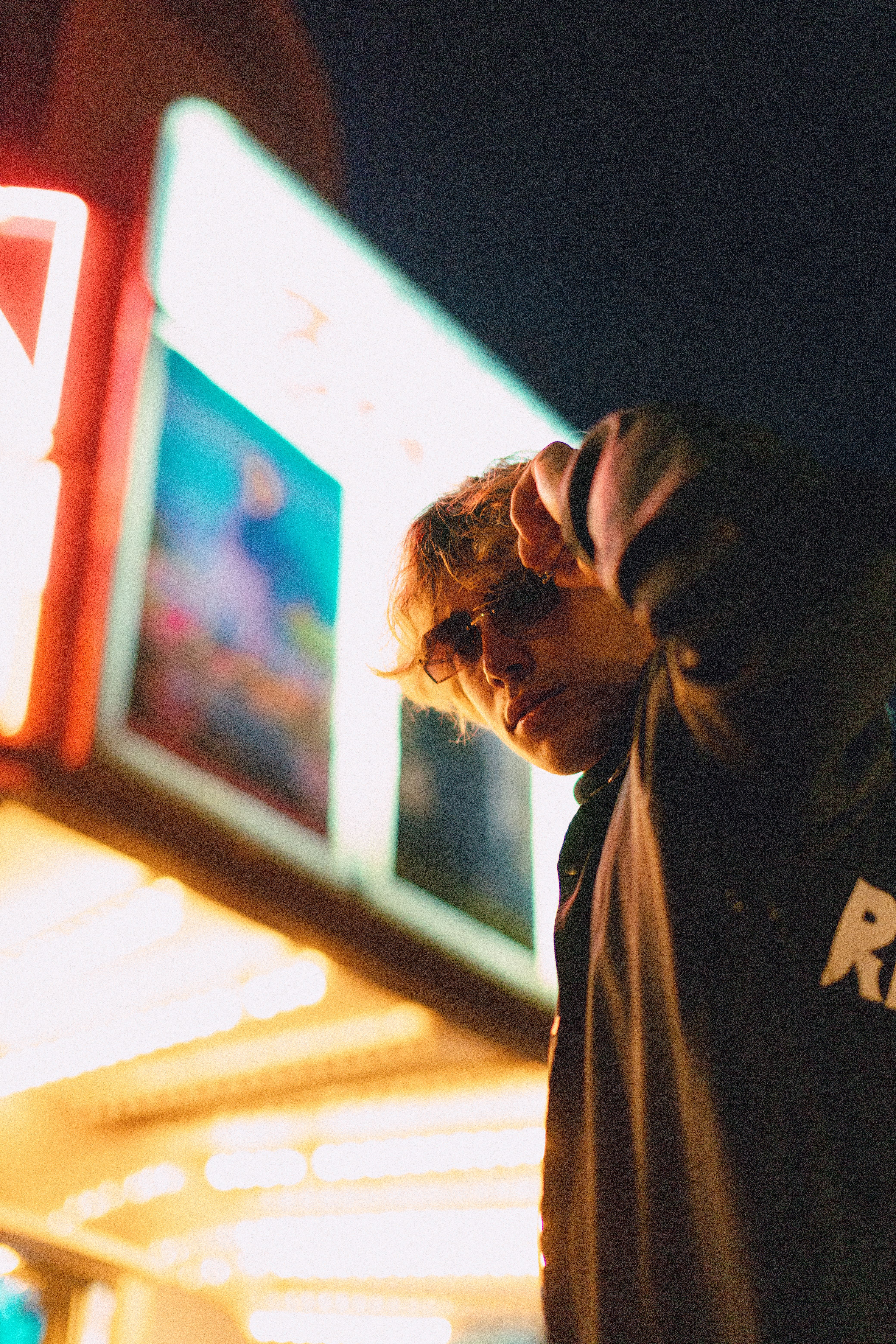 Low angle shot of a stylish man wearing sunglasses by neon lights at night.
