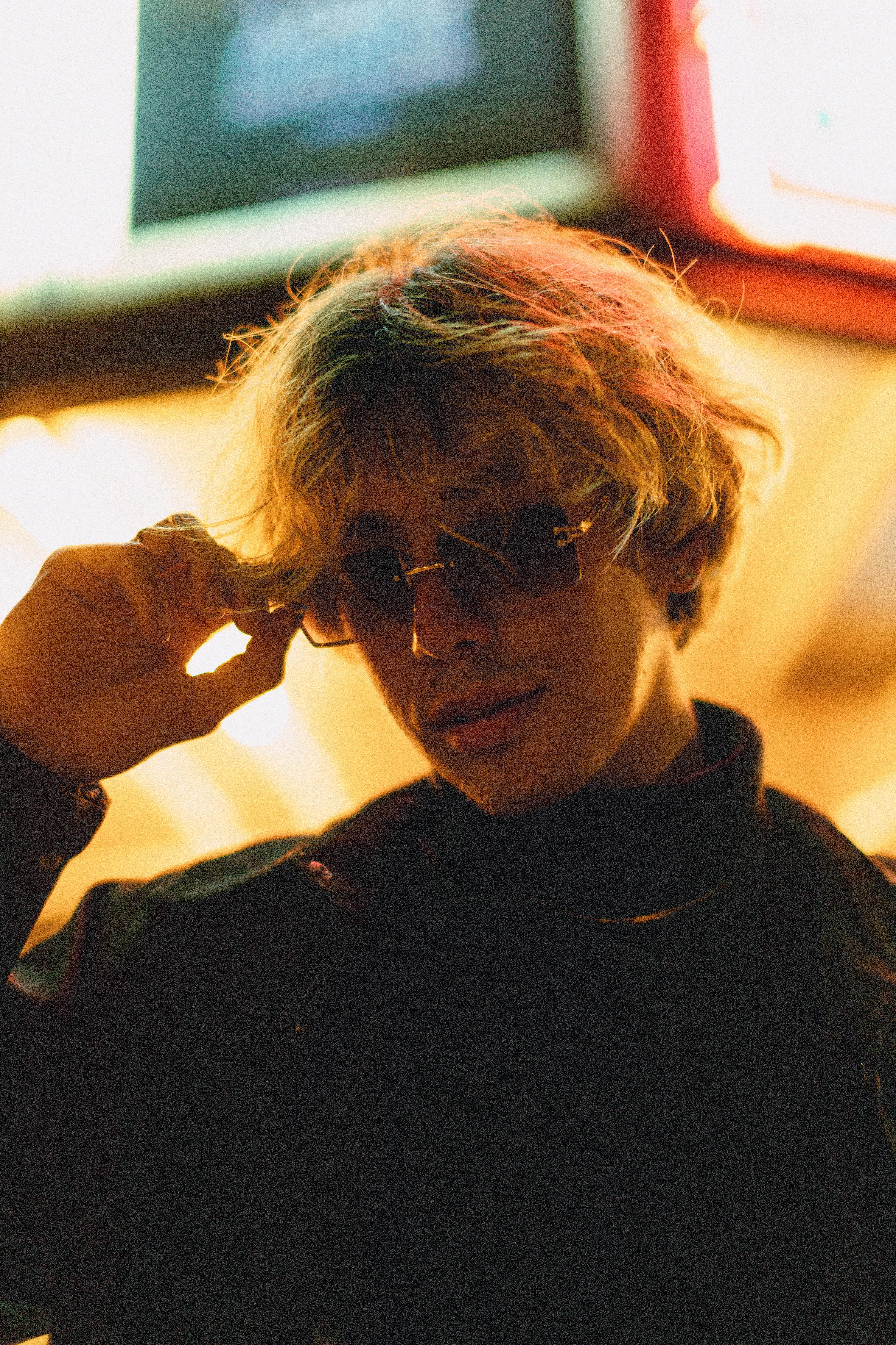 Portrait of a fashionable man with sunglasses, under neon lights at night.