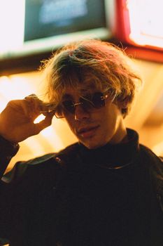 Portrait of a fashionable man with sunglasses, under neon lights at night.