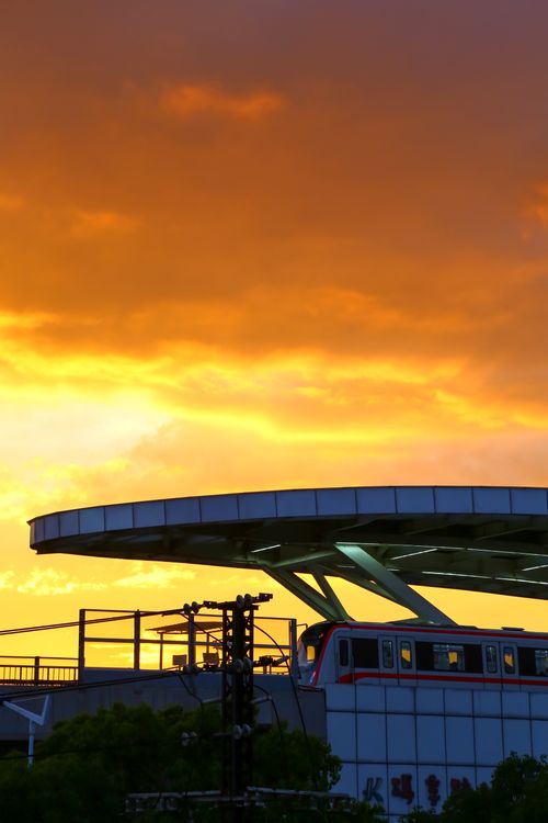 Free Modern train station with a vibrant orange sunset sky backdrop, creating a dramatic scene. Stock Photo