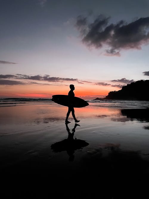 Free Silhouette of Man Holding Surfboard Stock Photo