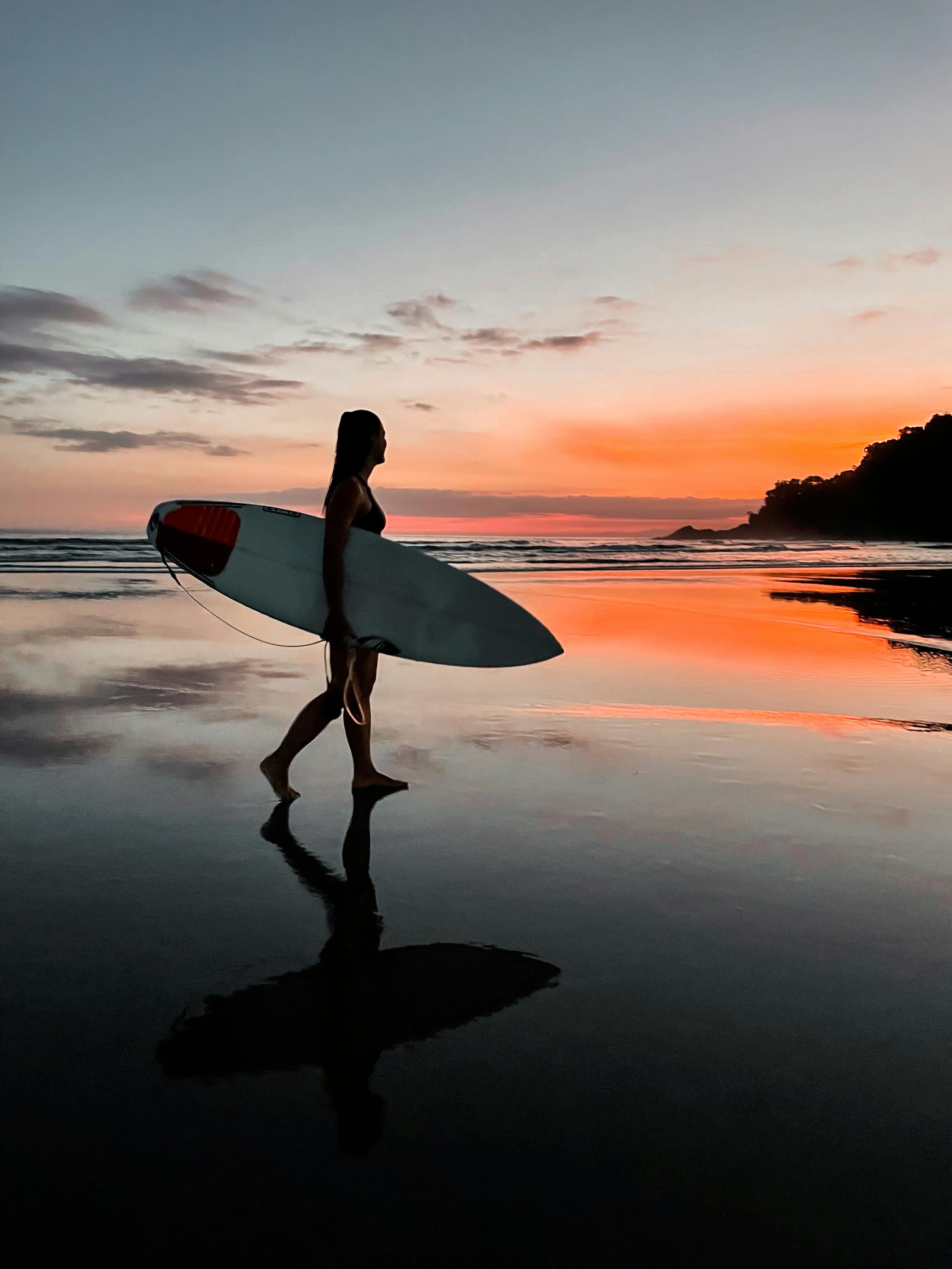 Silhouette of Woman Holding Surfboard · Free Stock Photo