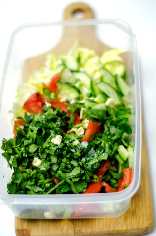 Free Fresh vegetable salad with cucumbers and herbs in a plastic container on a wooden board. Stock Photo