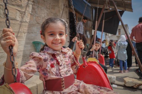 Free A cheerful young girl smiles while swinging outdoors in Idlib, Syria, capturing the innocence of childhood. Stock Photo