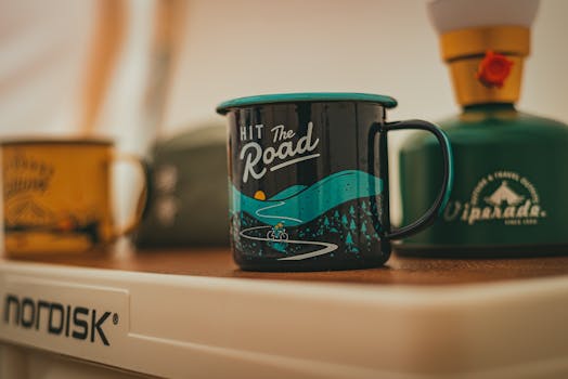 Artistic close-up of a camping mug with a travel theme against a blurred background.