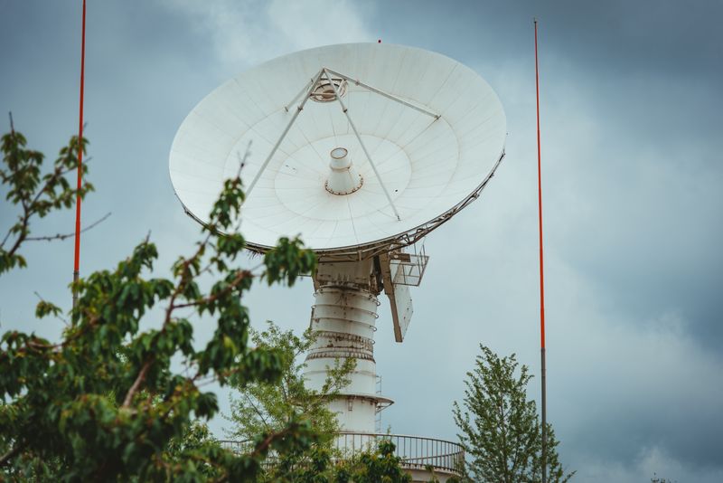 A large parabolic satellite communication dish points at the sky — the kind of Earth station that relays IoT data from remote sensors to orbit.