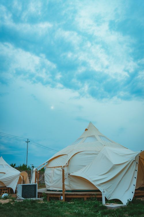 Free White glamping tents set against a vibrant blue sky, perfect for outdoor leisure and camping. Stock Photo