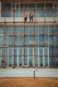 Construction workers on scaffolding repairing a building facade.