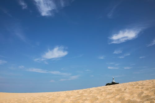 Free Person Sitting on Brown Sand Under Blue Sky Stock Photo