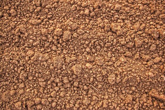 Detailed view of rough and dry brown soil, showcasing its natural texture.