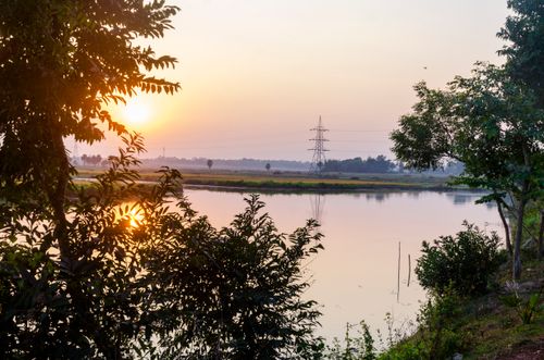 Free Tranquil sunset view with reflections over a river in a peaceful countryside setting. Stock Photo