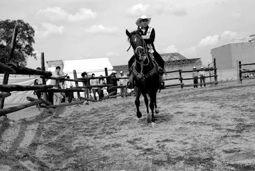 Grayscale Photo of Man Riding Horse