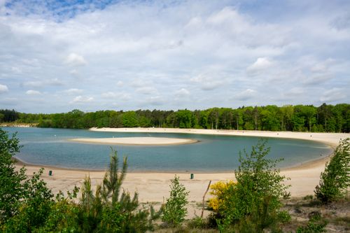 Free A serene lake surrounded by lush greenery, under a partly cloudy blue sky. Stock Photo